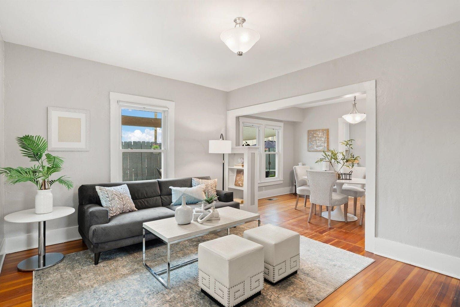 A living room with a couch , coffee table , ottomans and a rug.