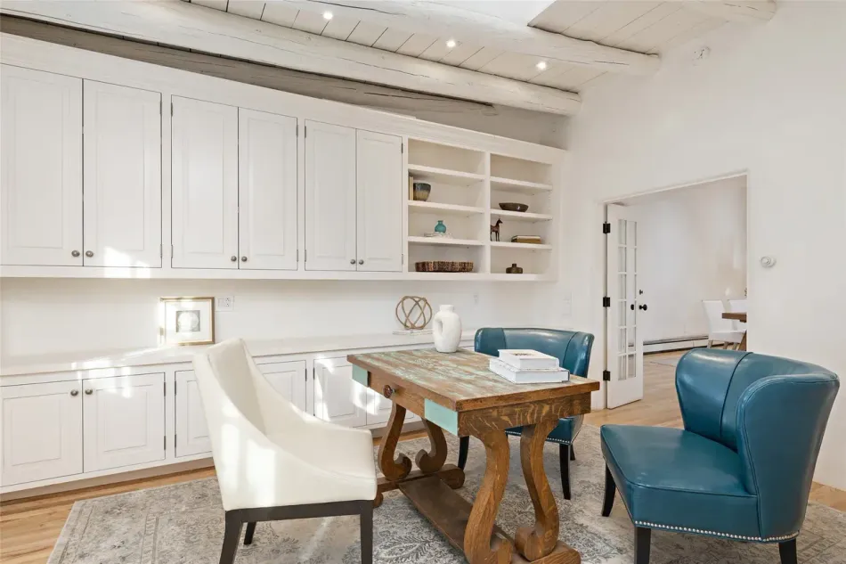 A living room with a wooden table and chairs and white cabinets.