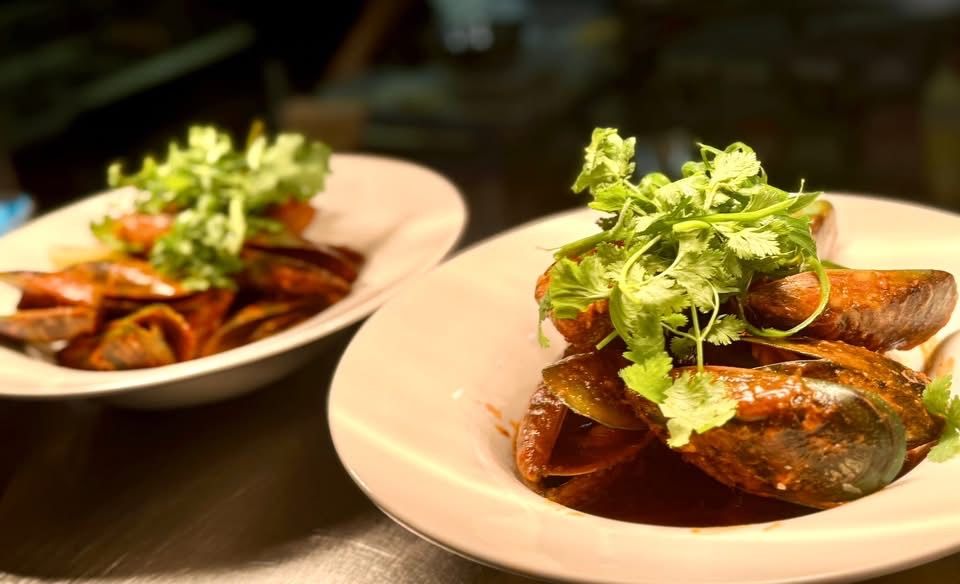 Two white bowls of plated food with cilantro garnish.