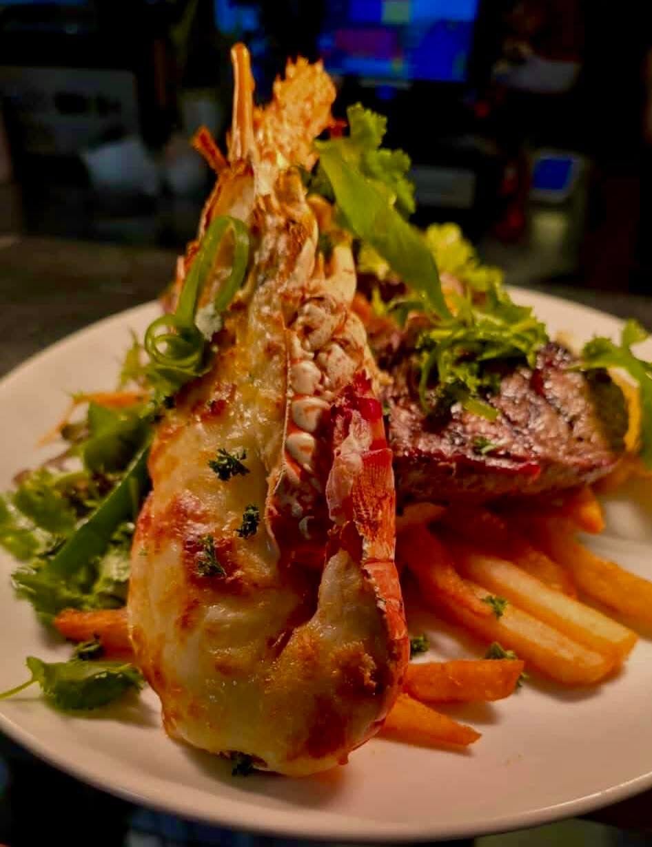 Plate of surf and turf: Grilled lobster and steak with fries and salad.