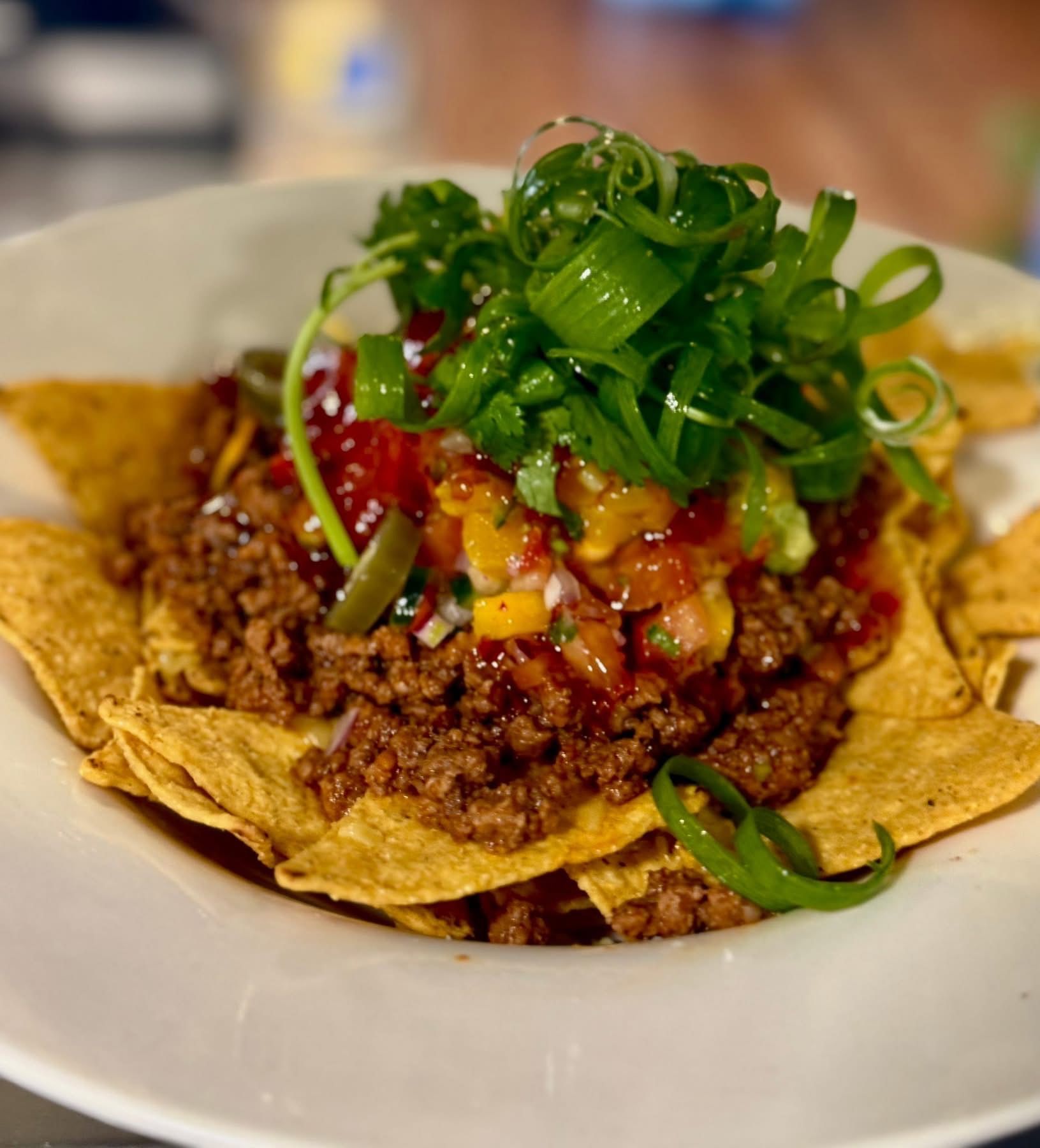 Nachos with ground meat, salsa, jalapeños, and green onions.
