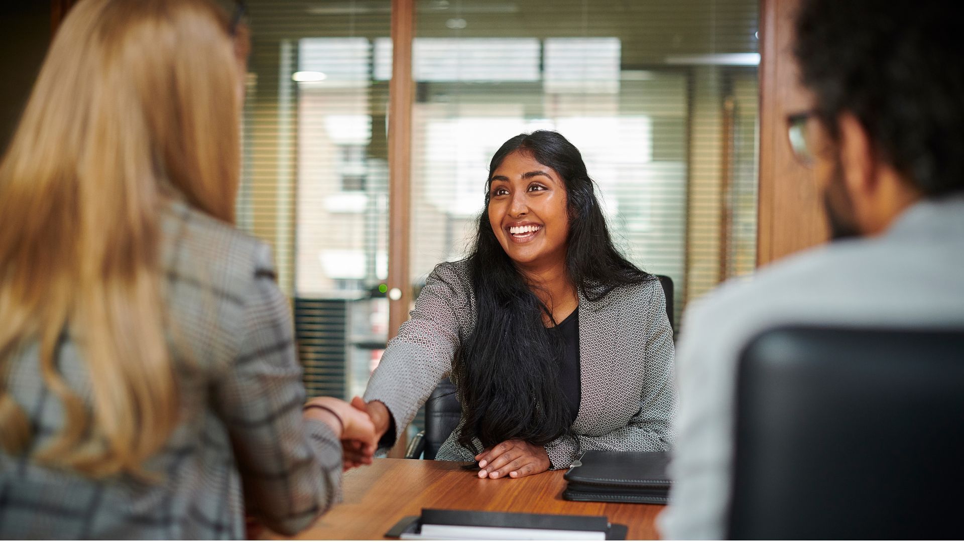 A group of people are standing around a computer in an office.
