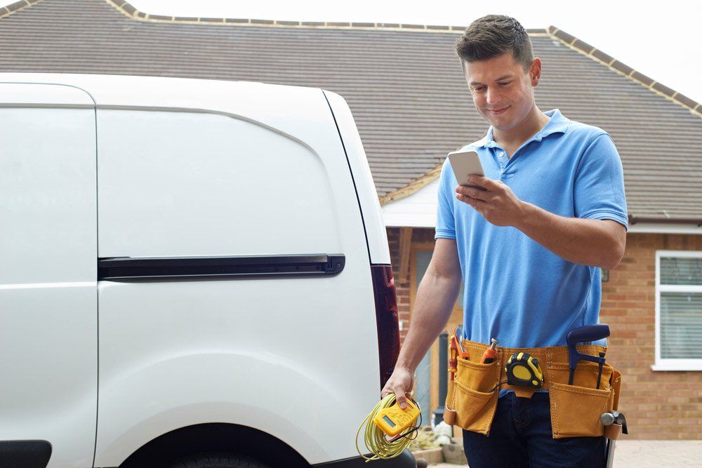 Electrician Checking Message On Mobile Phone — Electrical Services in Redlynch, QLD