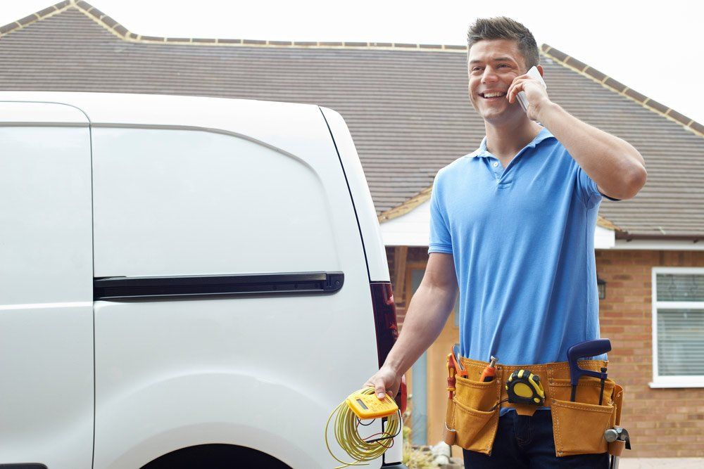 Electrician Standing Next To Van Talking On Mobile Phone — Emergency Electrician in Redlynch, QLD