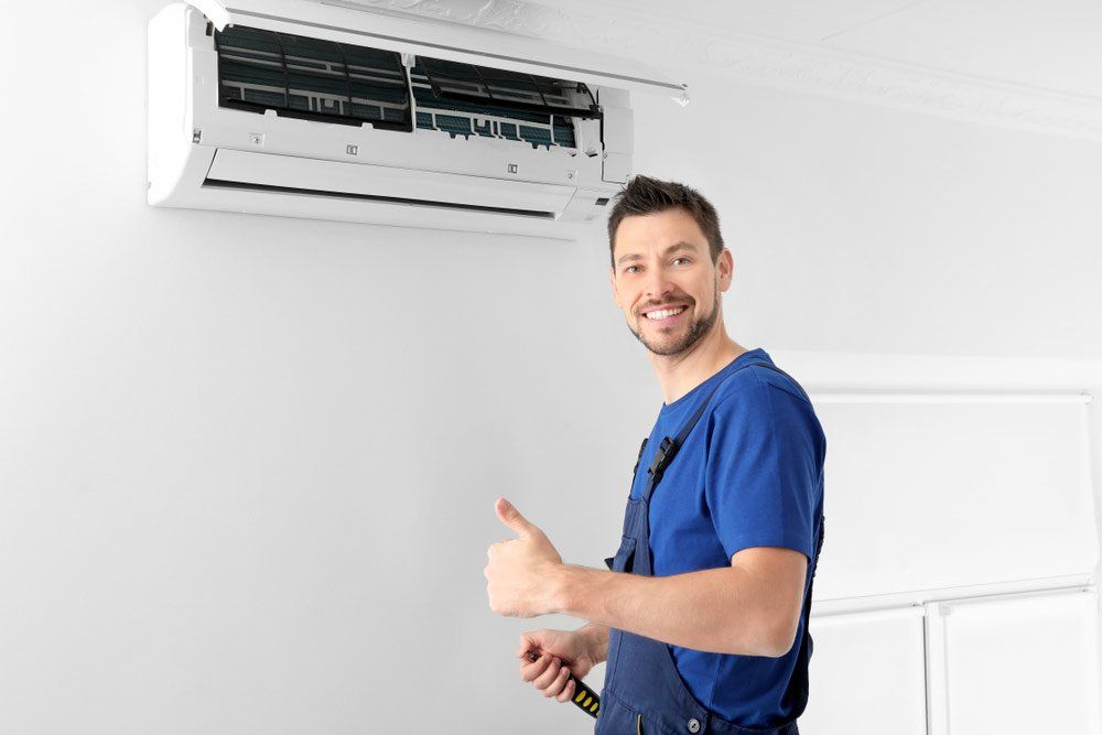 Male Technician After Successful Repair Of Air Conditioner — Electrical Services in Cairns, QLD