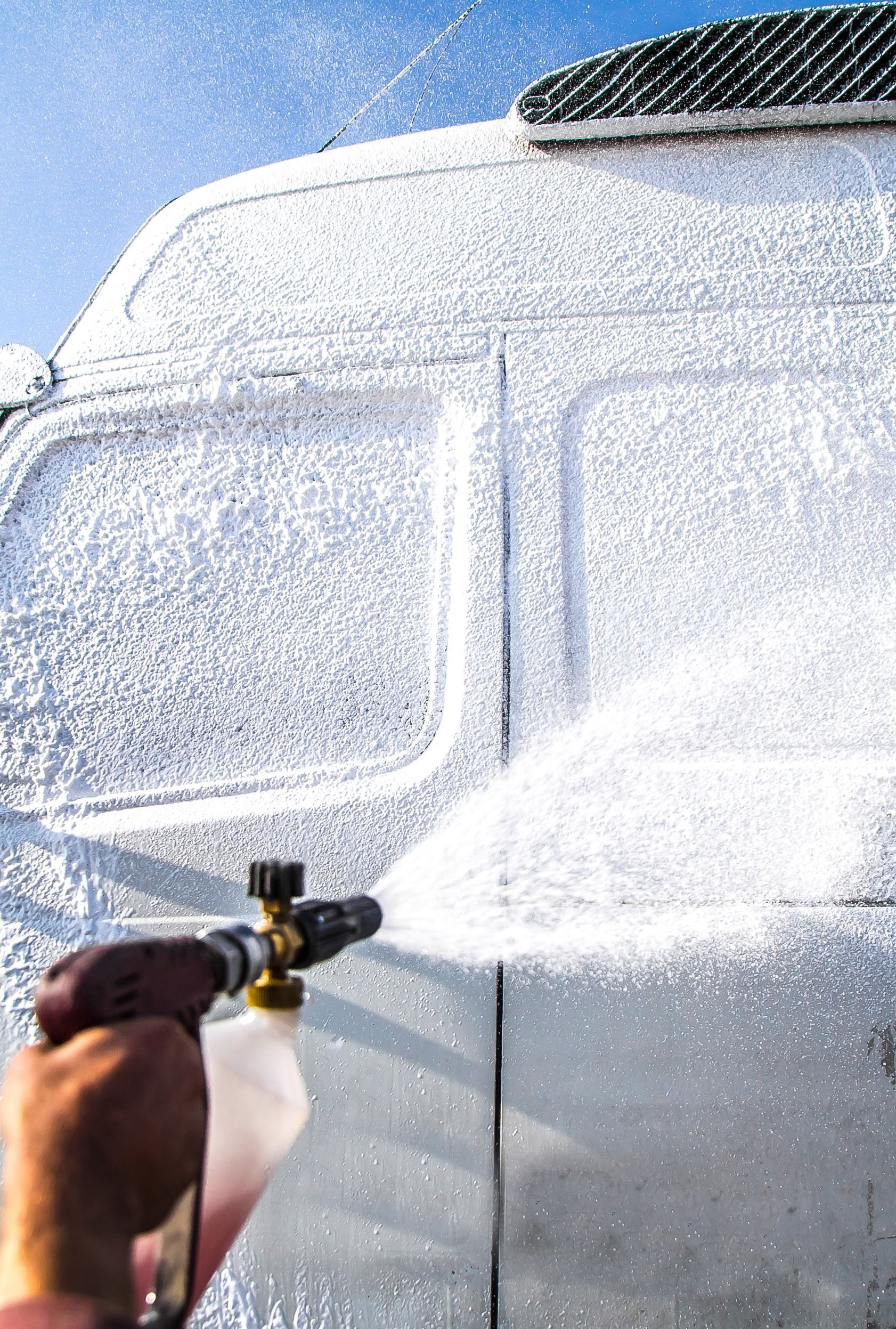 A person is spraying foam on the side of a van.