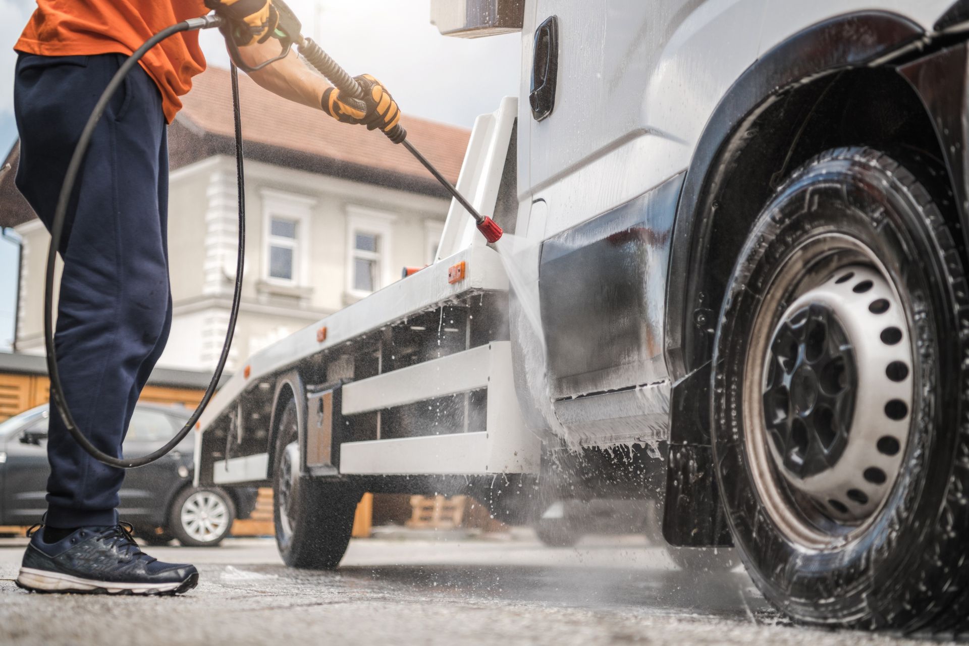 A man is washing a truck with a high pressure washer.