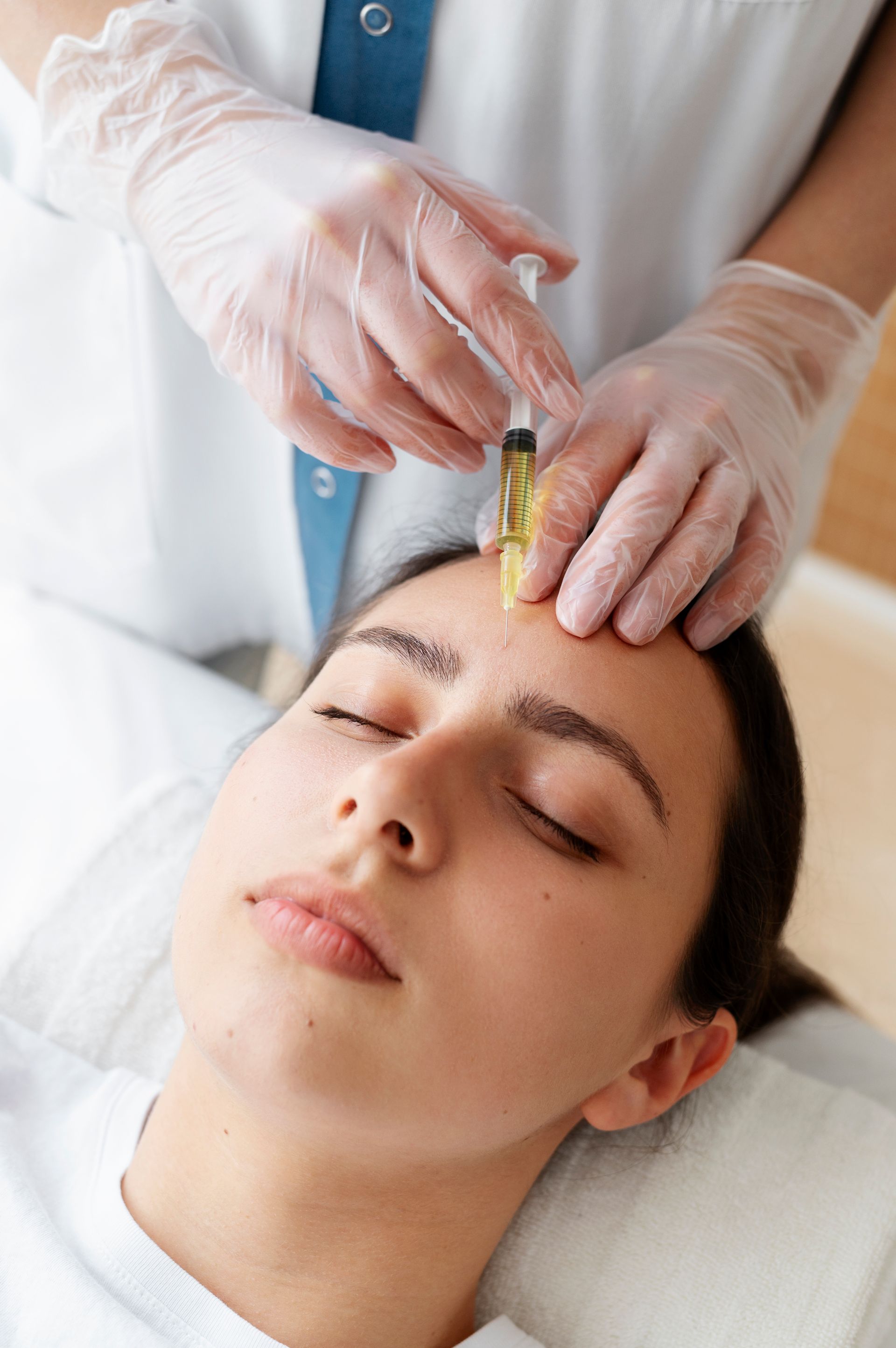 a woman is getting a botox injection in her forehead .