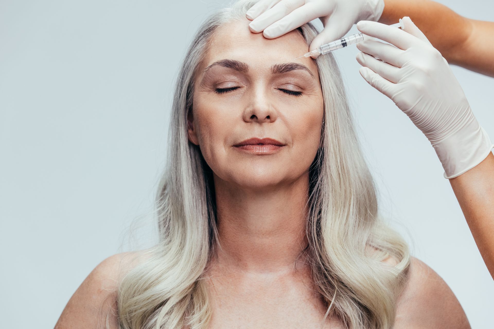 a woman is getting a botox injection in her forehead .