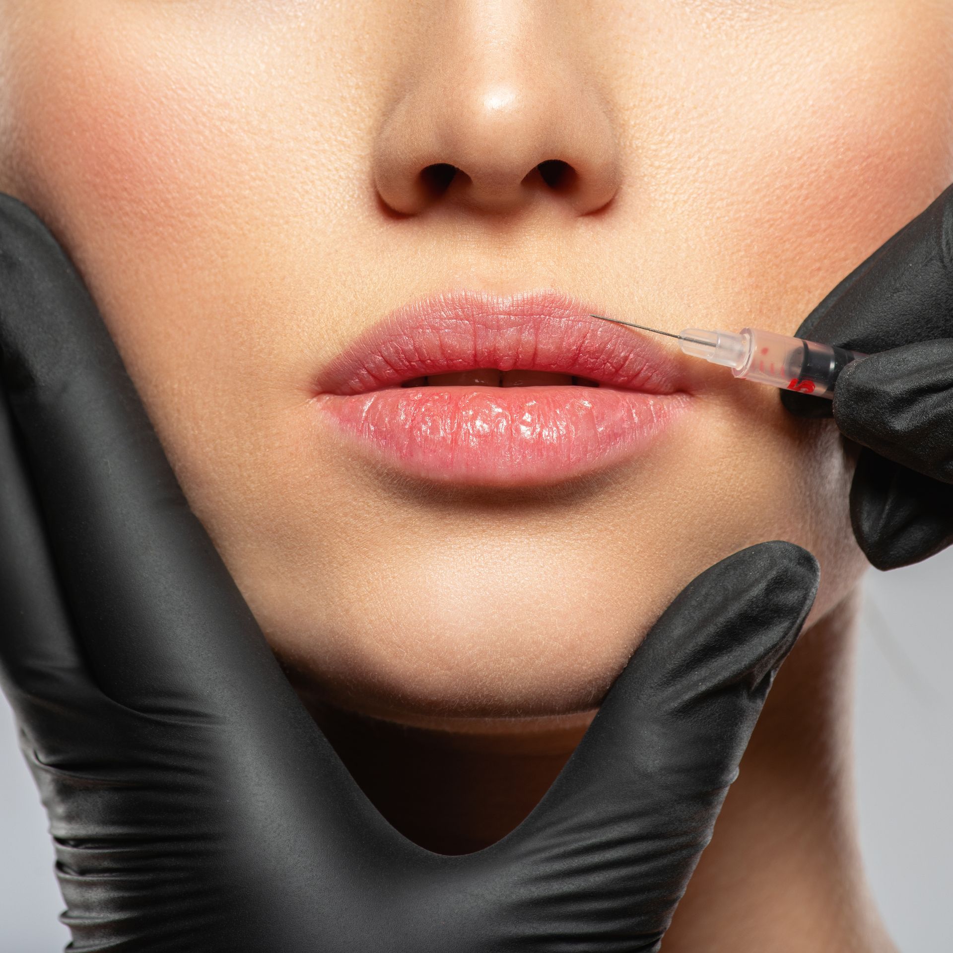 a woman is getting a botox injection in her lips .