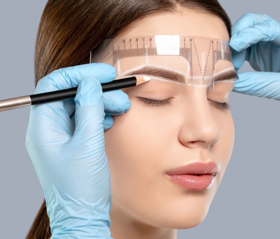A woman is getting her eyebrows drawn with a pencil.