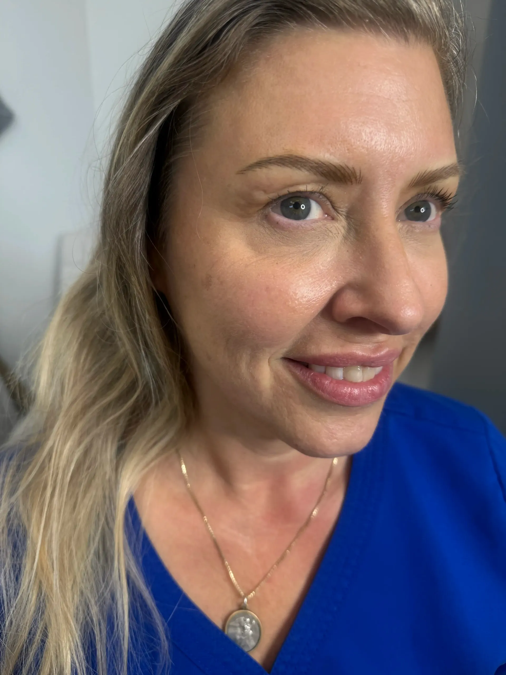 A close up of a woman wearing a blue shirt and a necklace.
