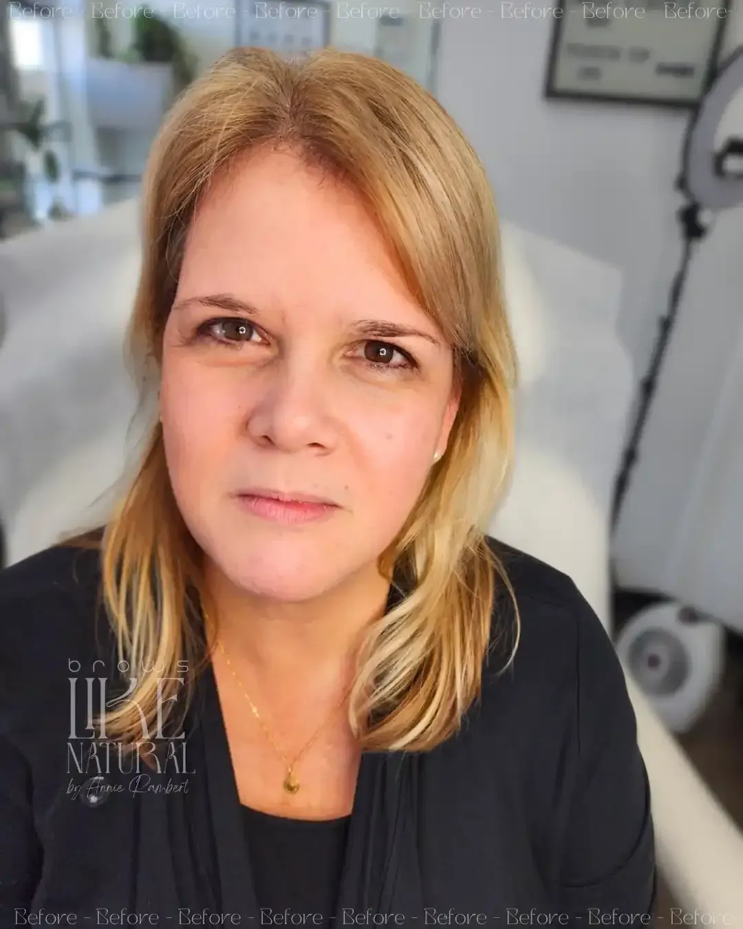 A woman with blonde hair is wearing a black shirt and a necklace