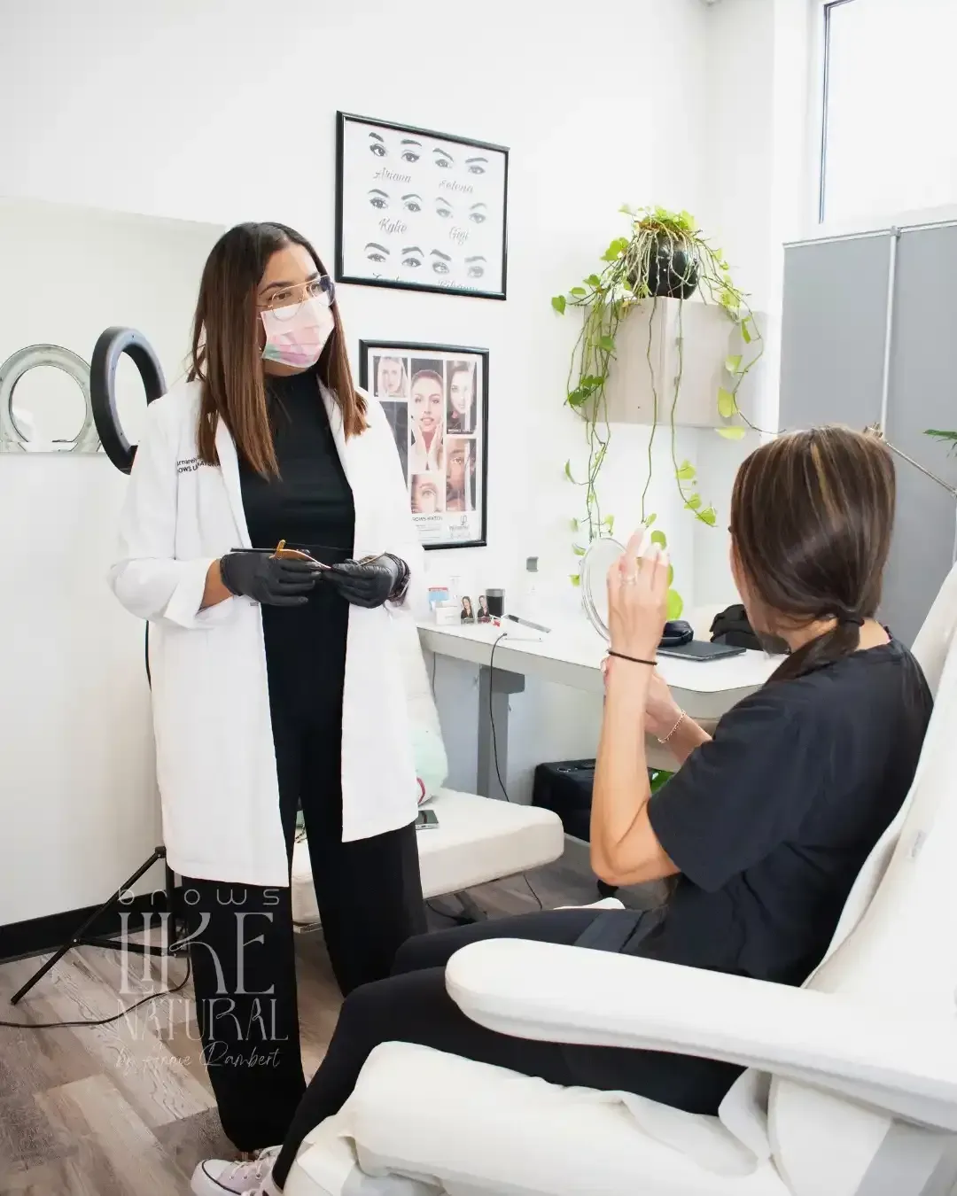 A woman wearing a mask is talking to a woman sitting in a chair.
