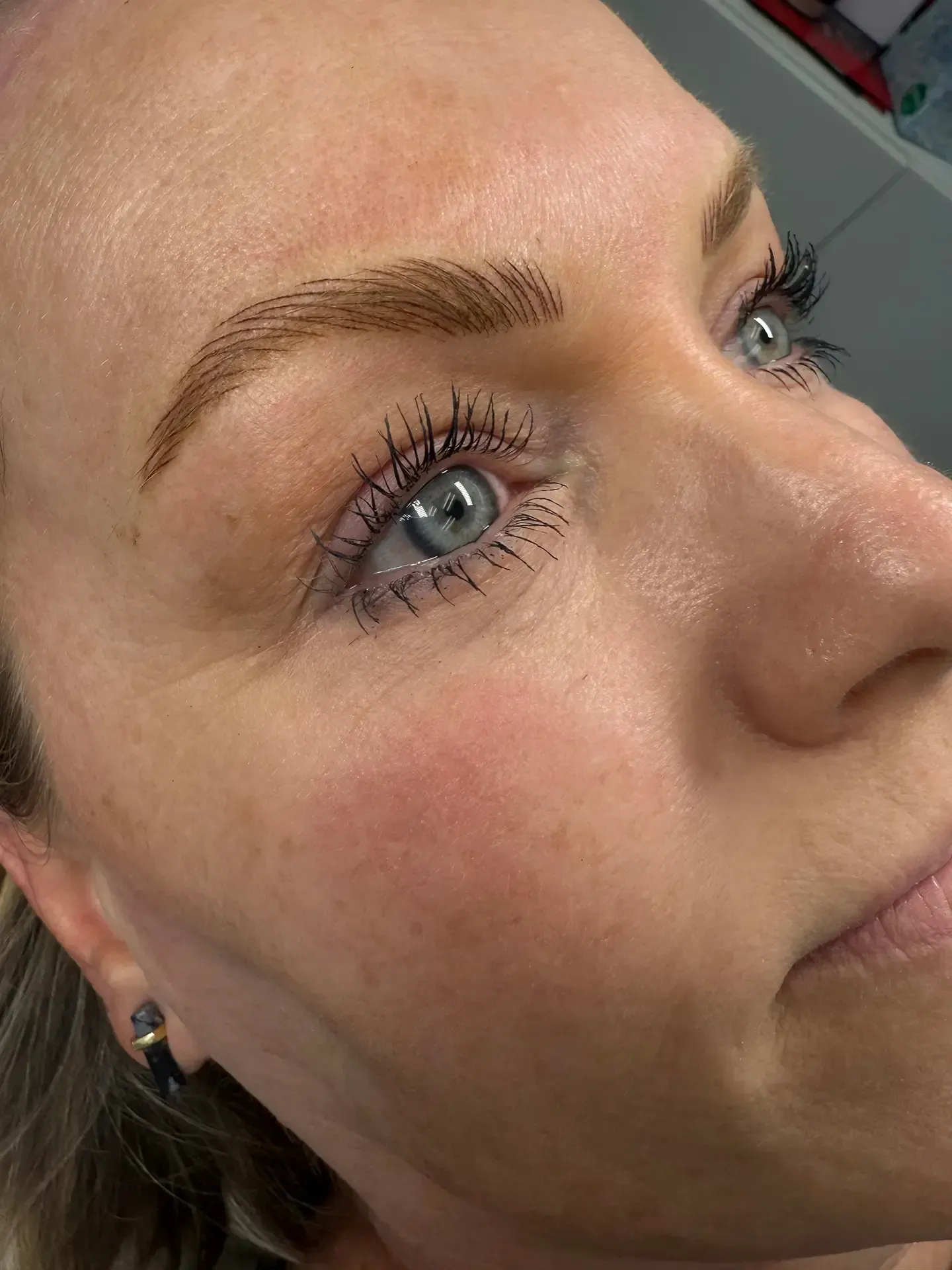 Woman with light skin and blue eyes, wearing mascara and having microbladed eyebrows.