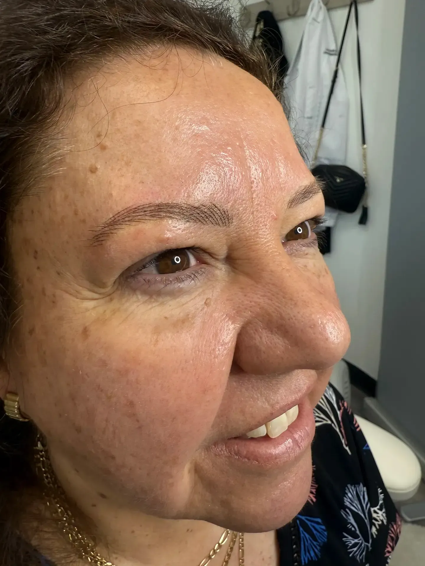 Woman with semi-permanent eyebrow makeup, looking slightly to the side.