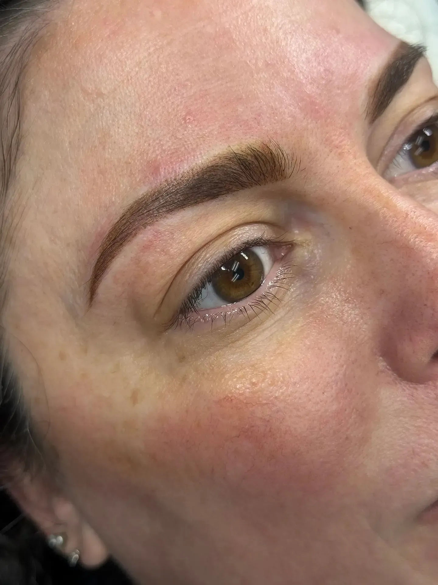 Close-up of a woman's face with professionally-done dark brown eyebrows. She has brown eyes and her skin is fair.