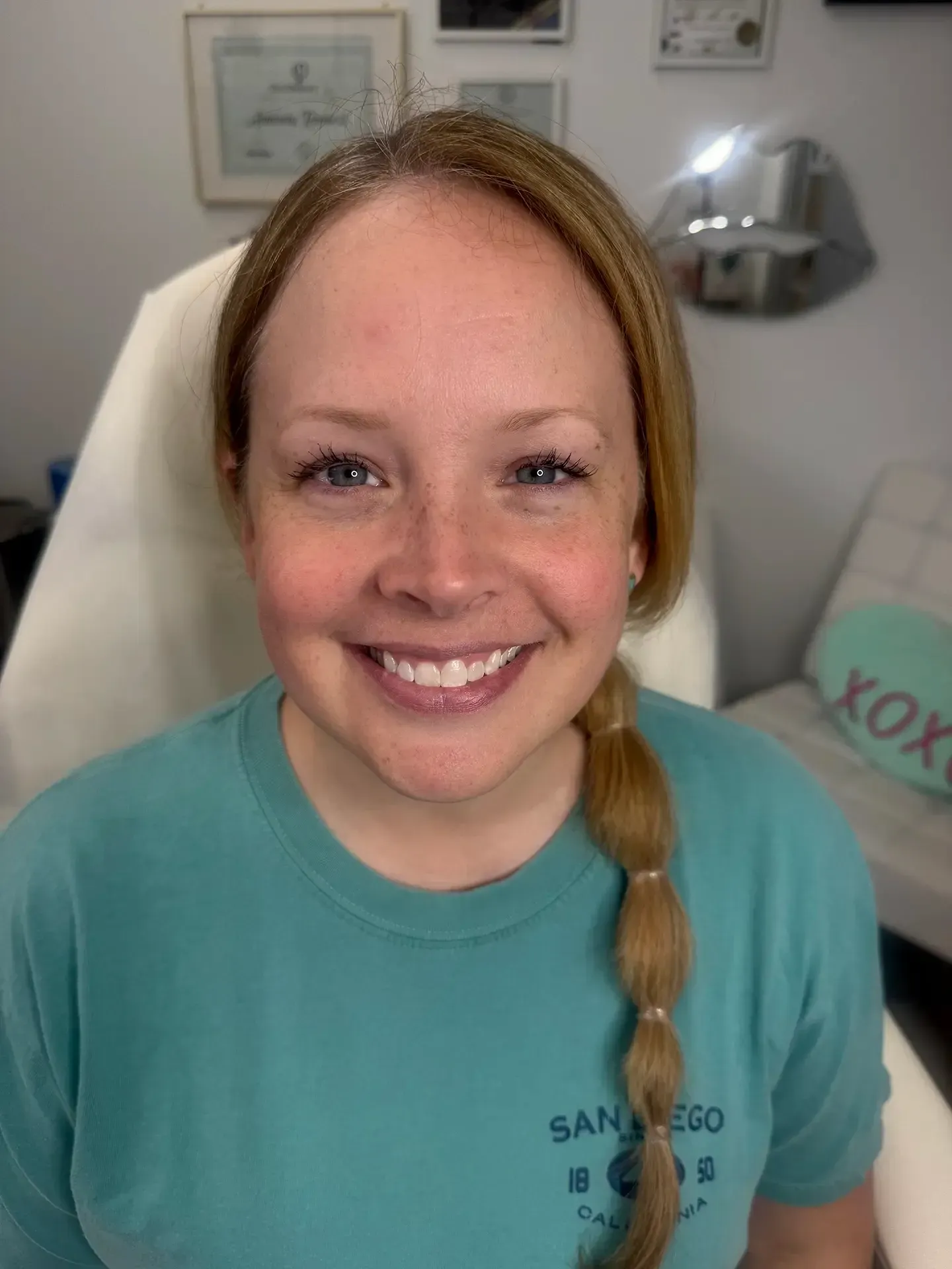 Smiling woman with blonde hair pulled back in a ponytail wearing a teal t-shirt.