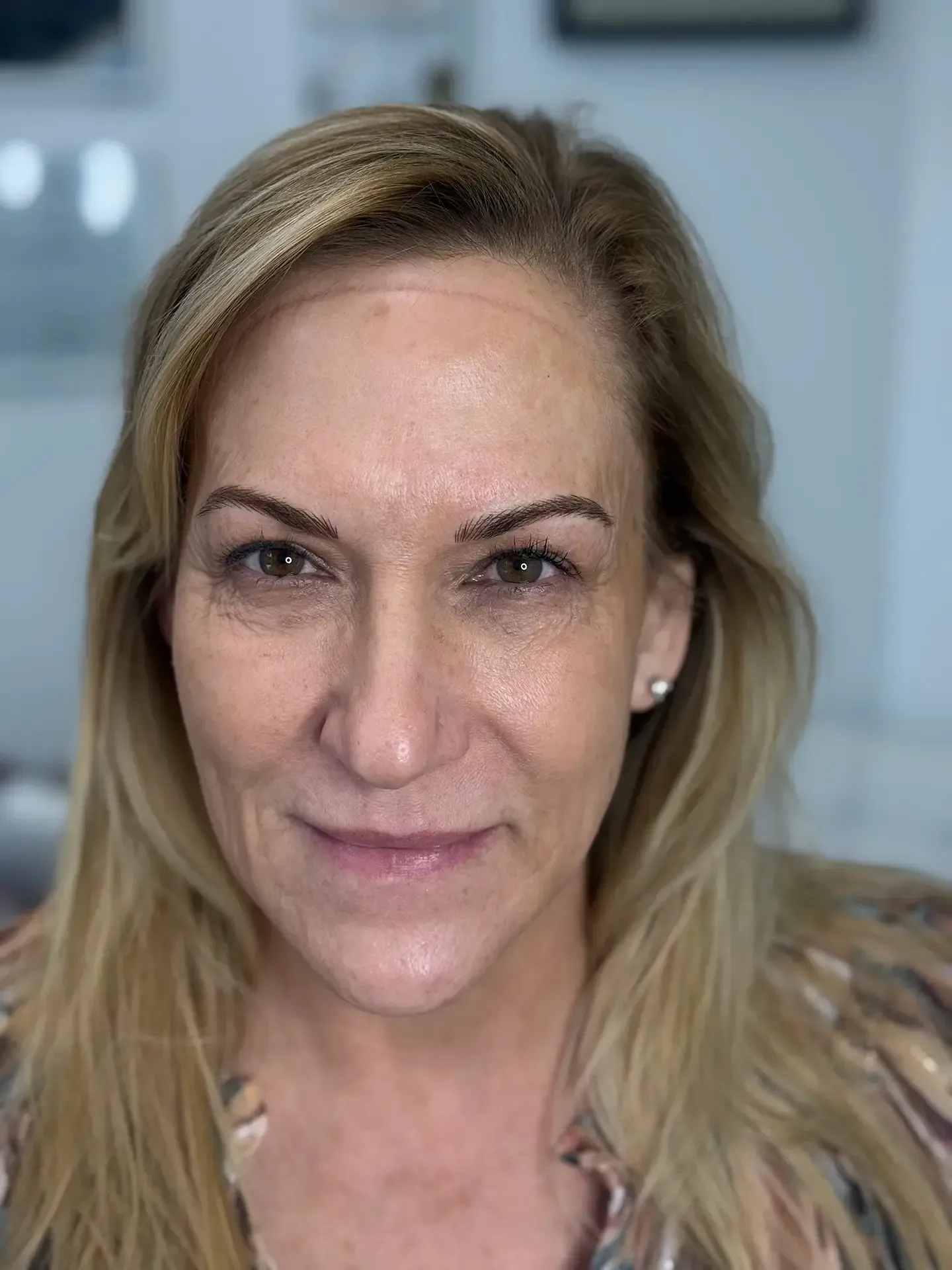 Woman with blonde hair and neutral makeup, looking directly at the camera with a slight smile; indoors.