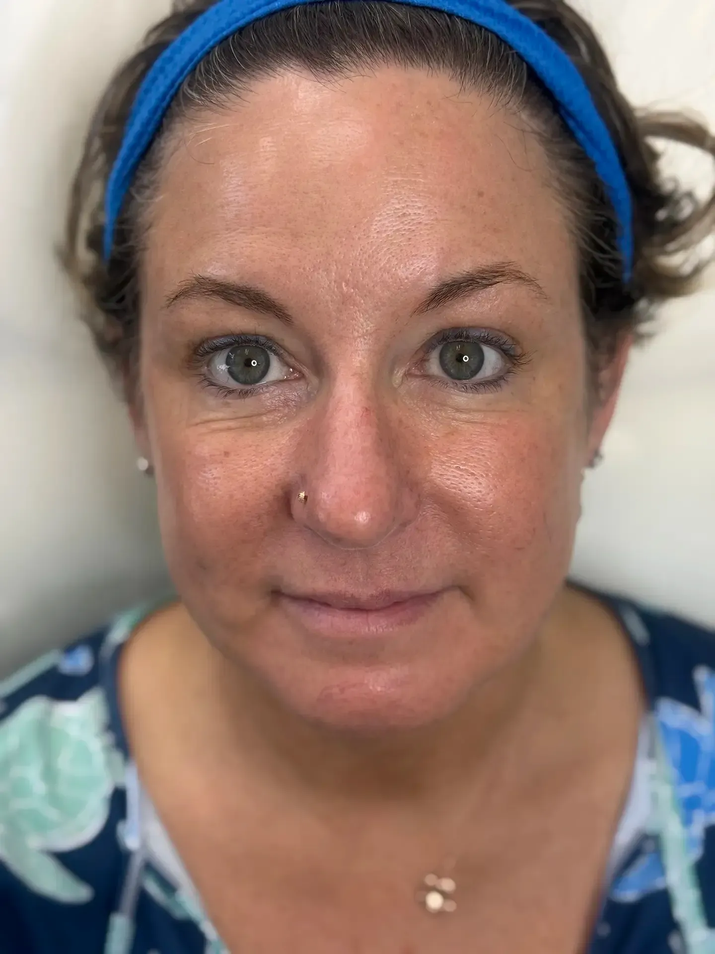 Woman with fair skin, wearing a blue headband, looking directly at the camera. She has dark eyes and a slight smile.