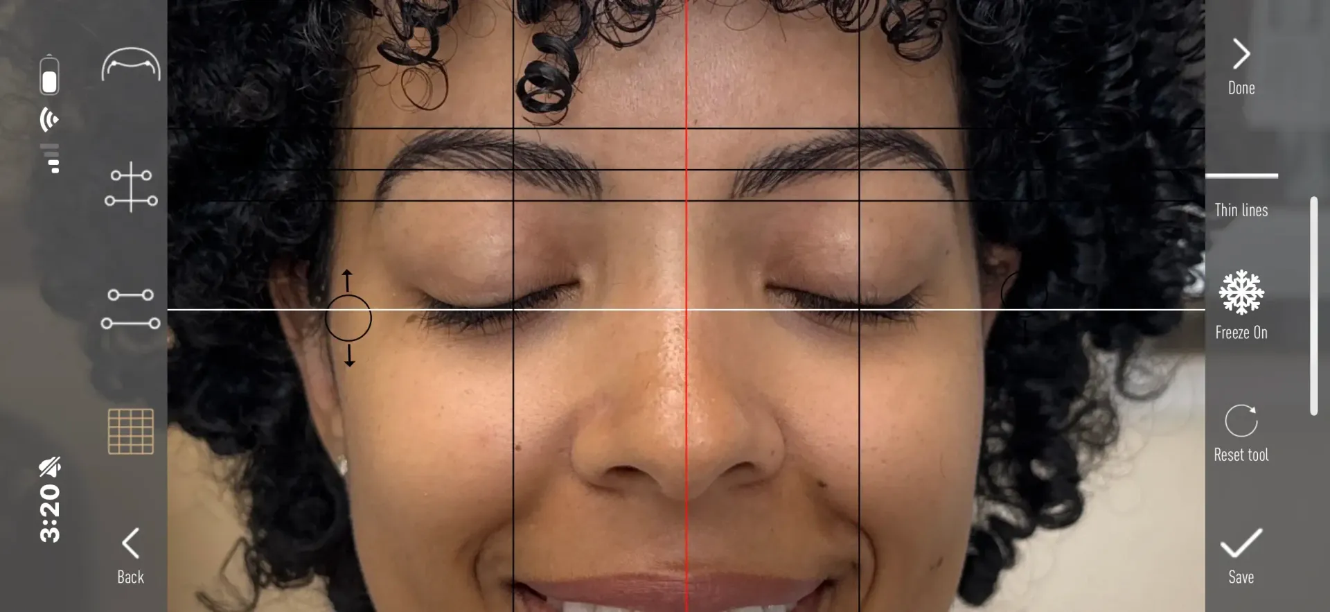 Face of a woman with closed eyes, overlaid with alignment guides, smiling. A red and black crosshair and horizontal lines assist with symmetry assessment.