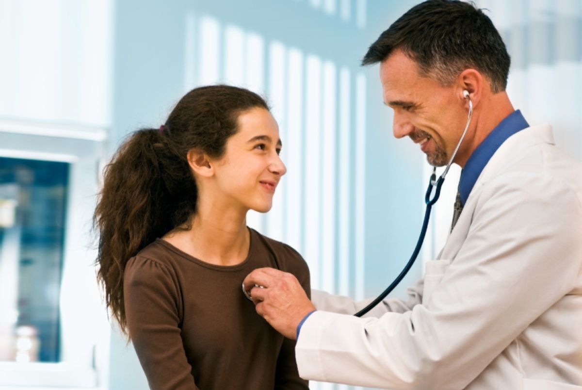 Doctor listening to a patient's chest with a stethoscope in a medical office.
