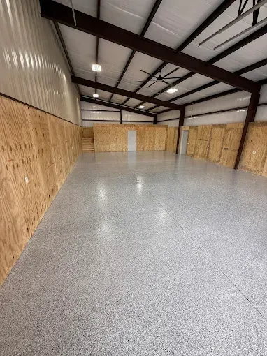 Woman in straw hat smiles, holding wine glass near a lake.
