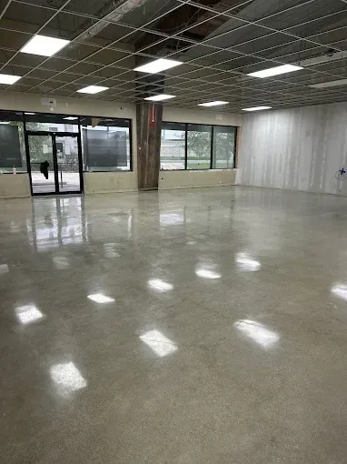 Woman in straw hat smiles, holding wine glass near a lake.