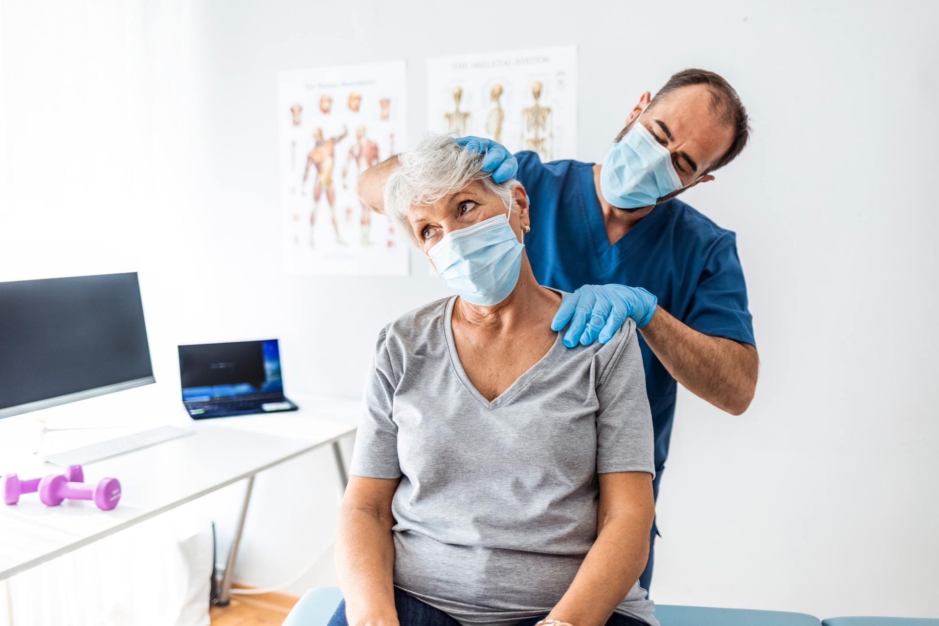 A man is giving an older woman a neck massage while wearing a mask.