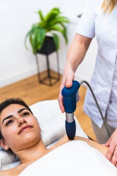 A woman is laying on a bed getting a massage with a machine.