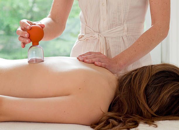 A woman is getting a cupping massage on her back.