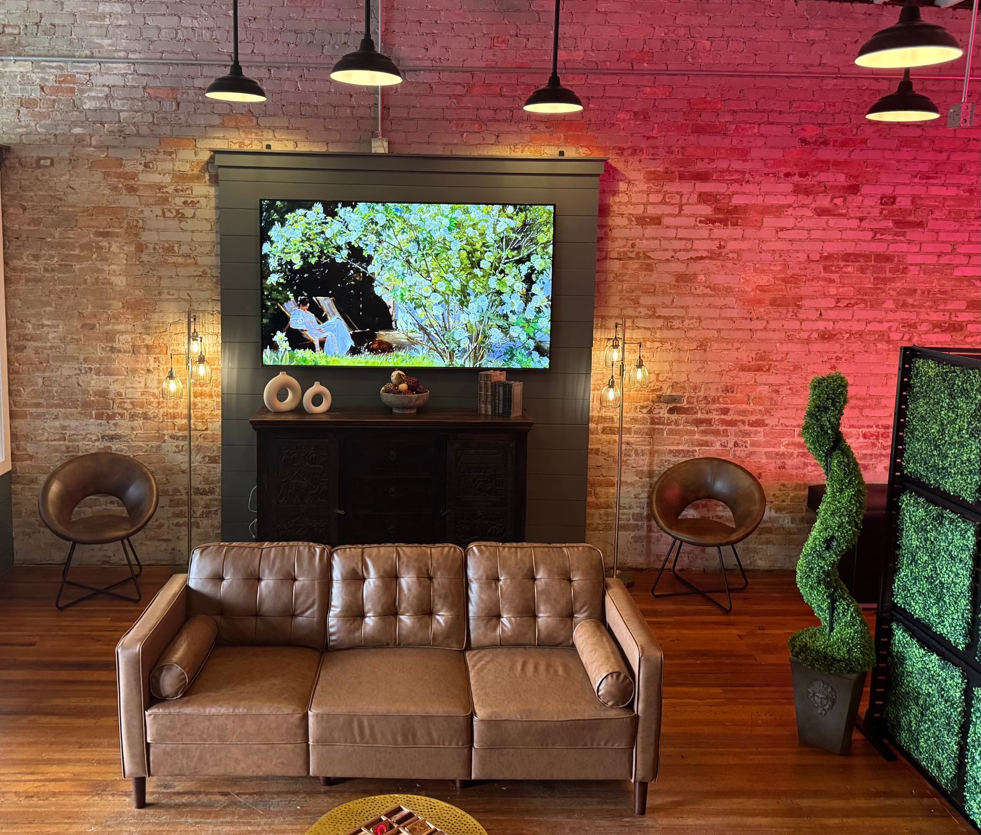 Living room with leather couch, brick wall, TV, and decorative lights.