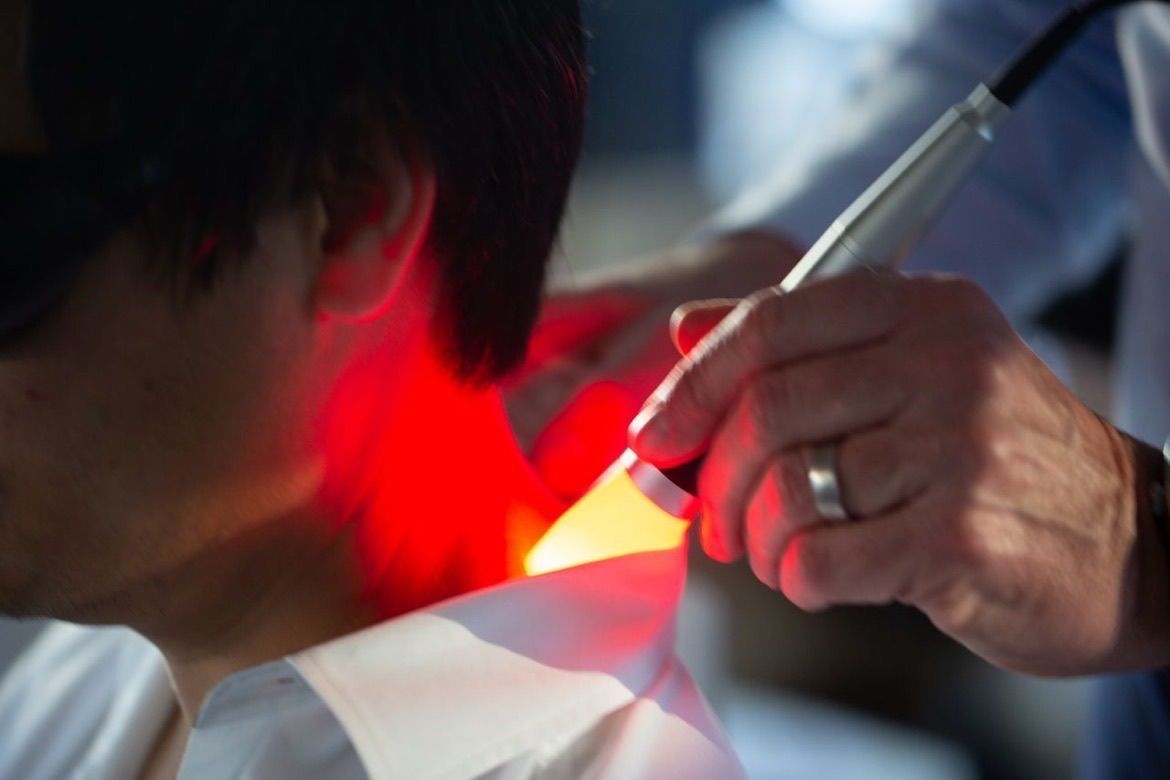 A woman is laying on a bed getting a massage with a machine.