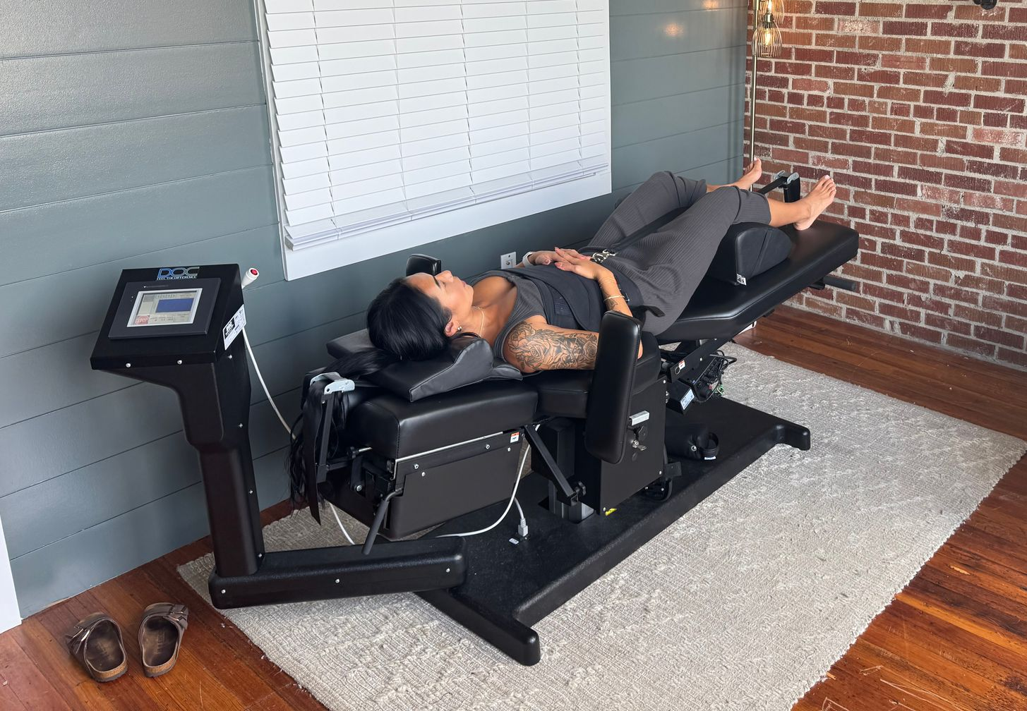 Man sitting at a desk, clutching his neck, likely experiencing pain. Laptop and papers nearby.