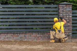 Professional fencer repairing slat fencing on a residential front yard in Melville WA.