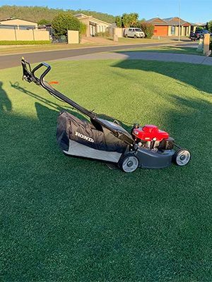 A Honda lawn mower is sitting on top of a lush green lawn.