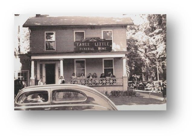 A black-and-white photo of a two-story Earle Little Funeral Home building with people sitting on the front porch.