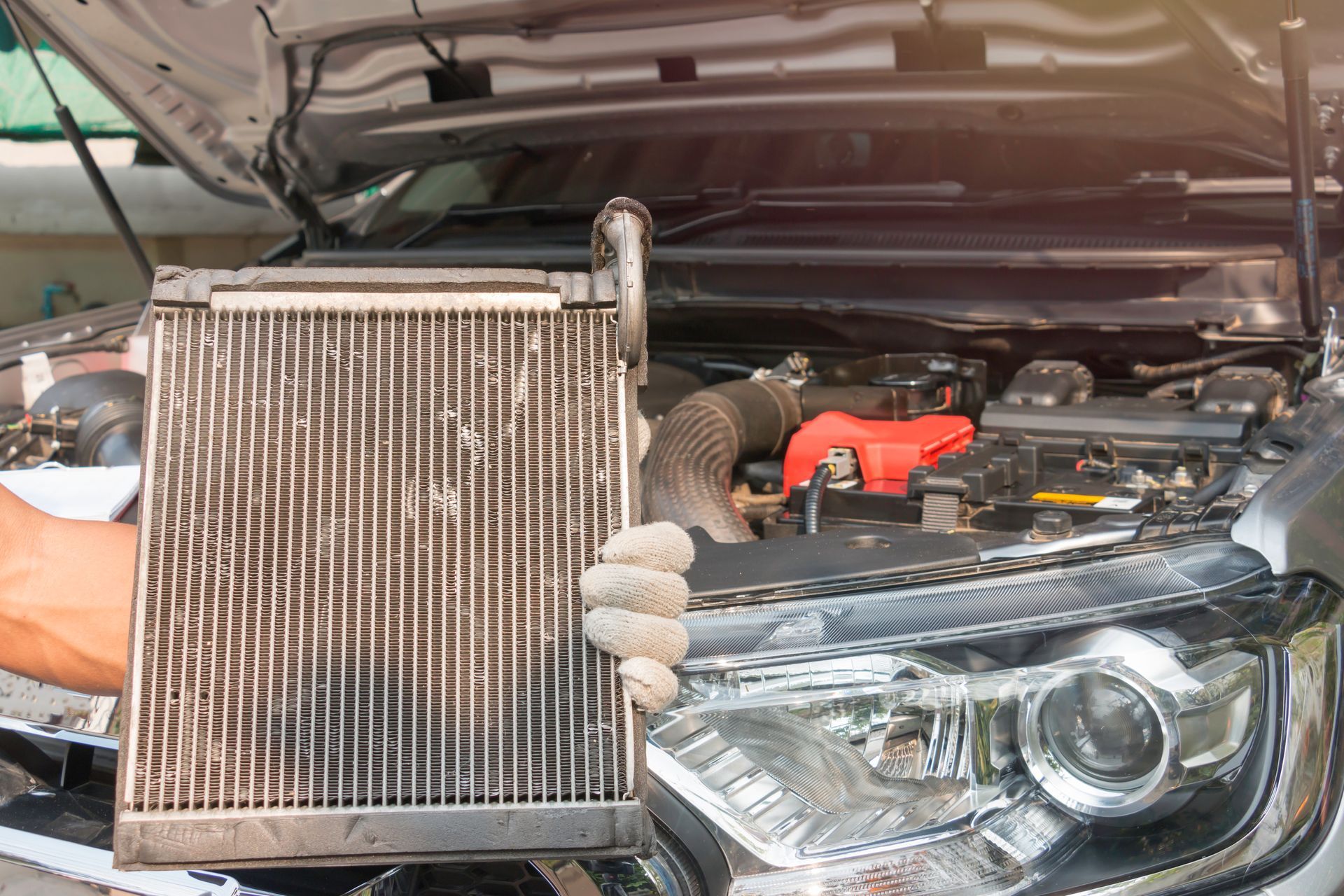 Mechanic positioning a car radiator in front of an open engine bay during replacement work. Mechanic positioning a car radiator in front of an open engine bay during replacement work.