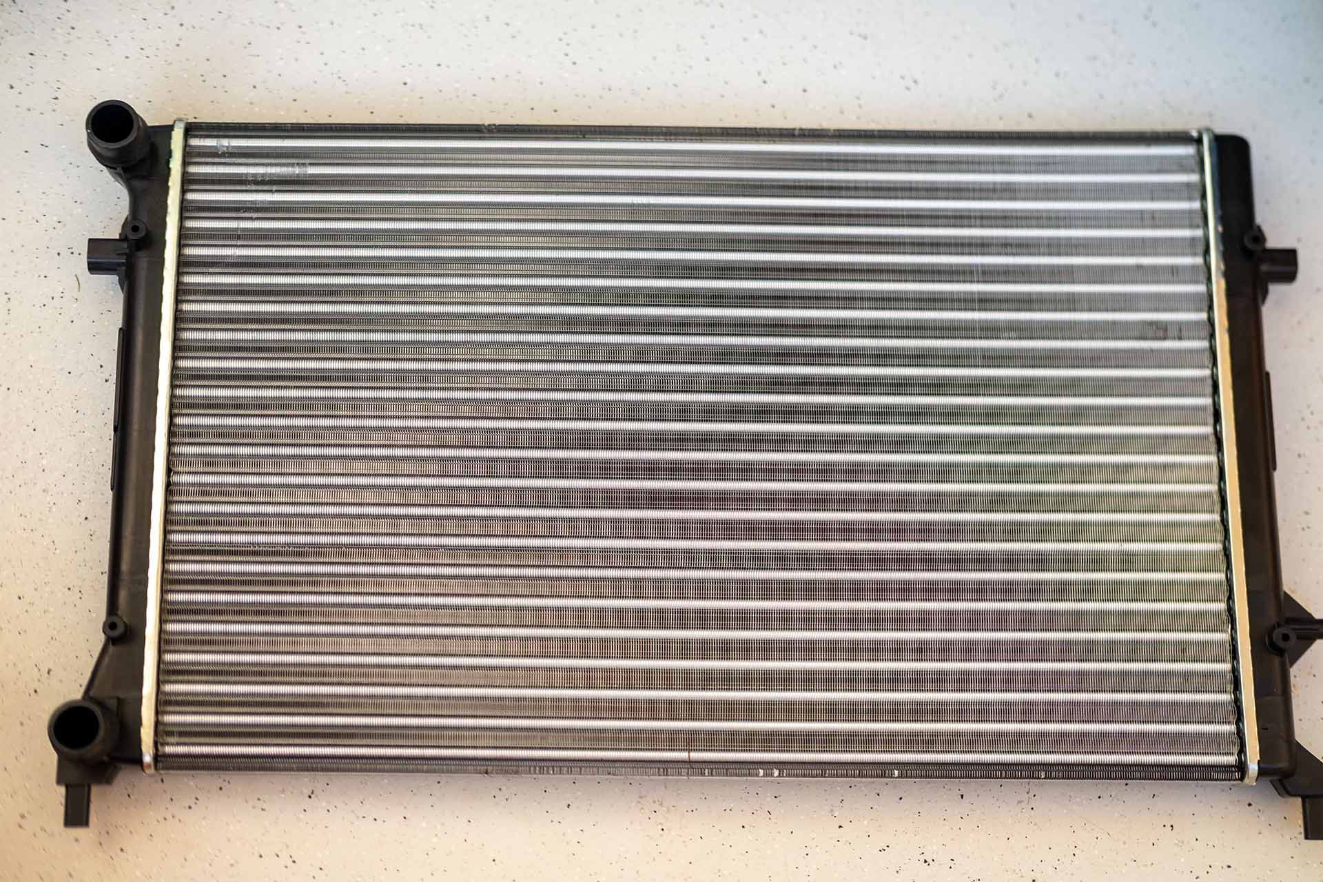 Shiny new car radiator with clean fins and polished finish, ready to install.