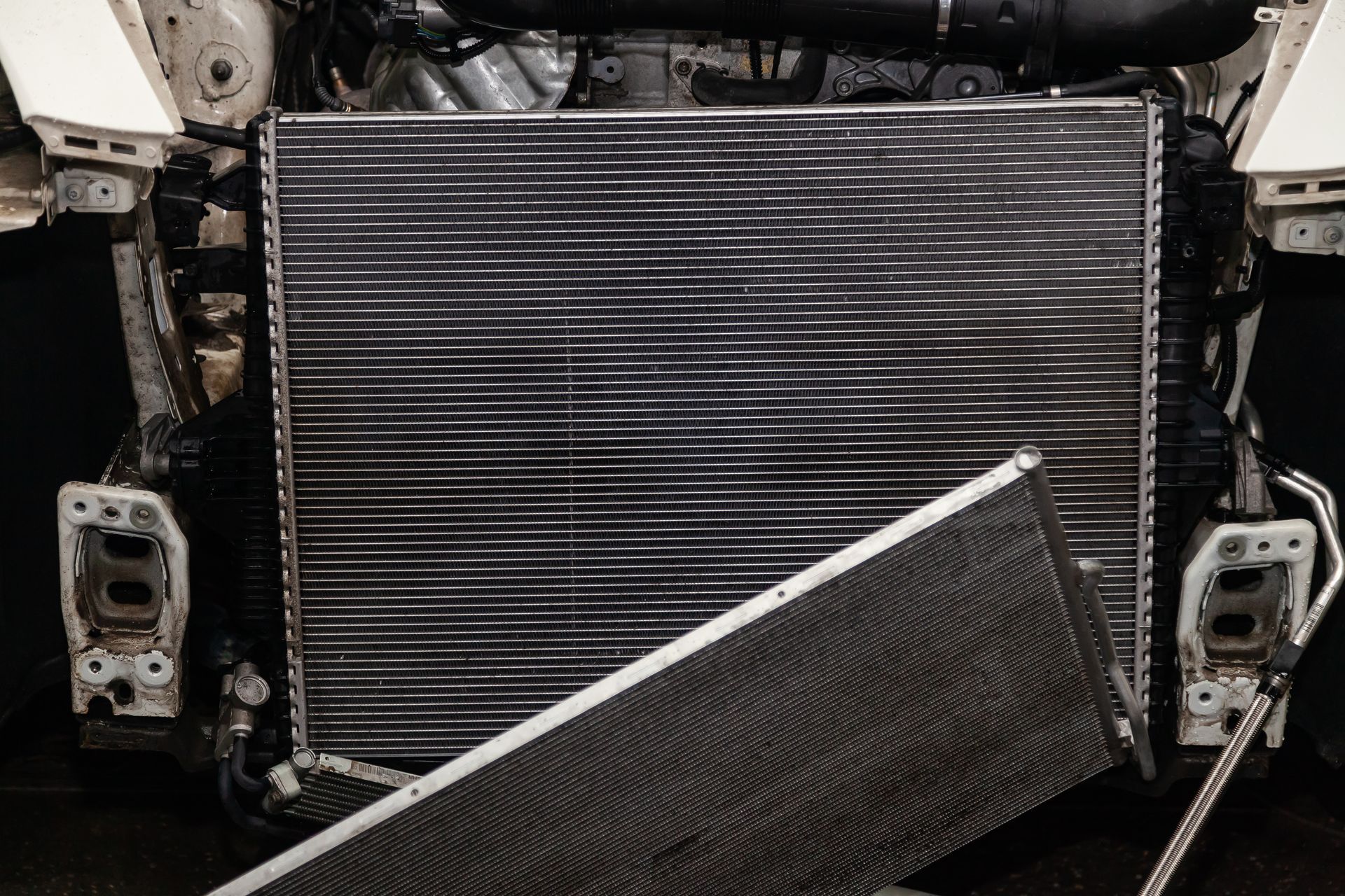 Car radiator removed during engine repair, with cooling fins and frame exposed in the shop.