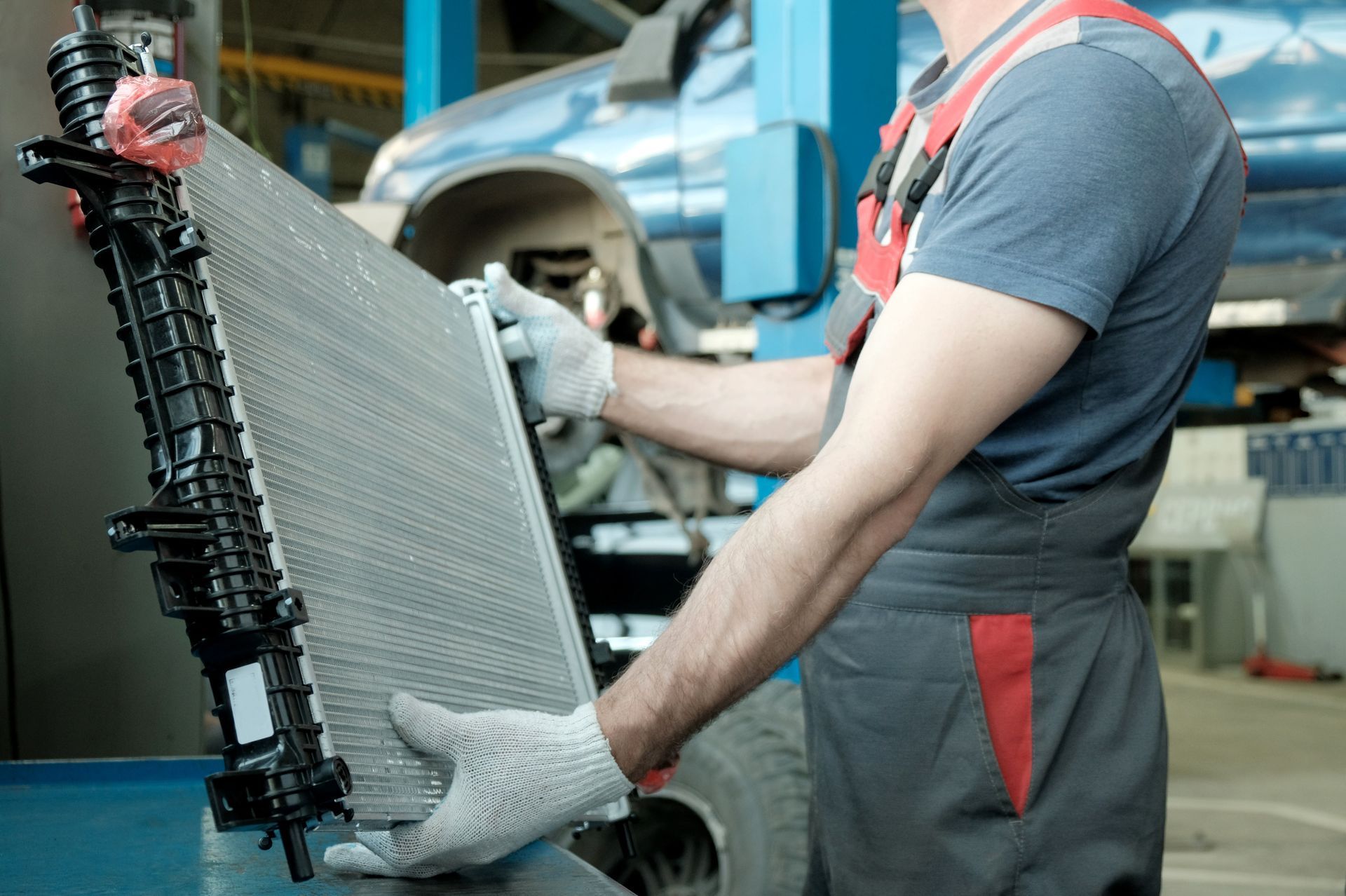 Auto technician holding a car radiator in a vehicle repair workshop. Auto technician holding a car radiator in a vehicle repair workshop.