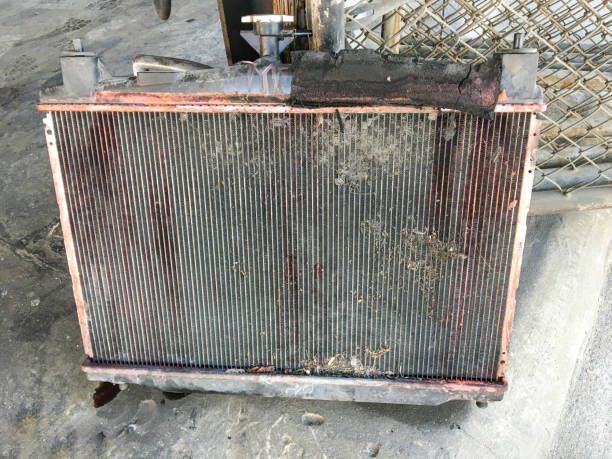 A radiator is sitting on the ground next to a chain link fence.