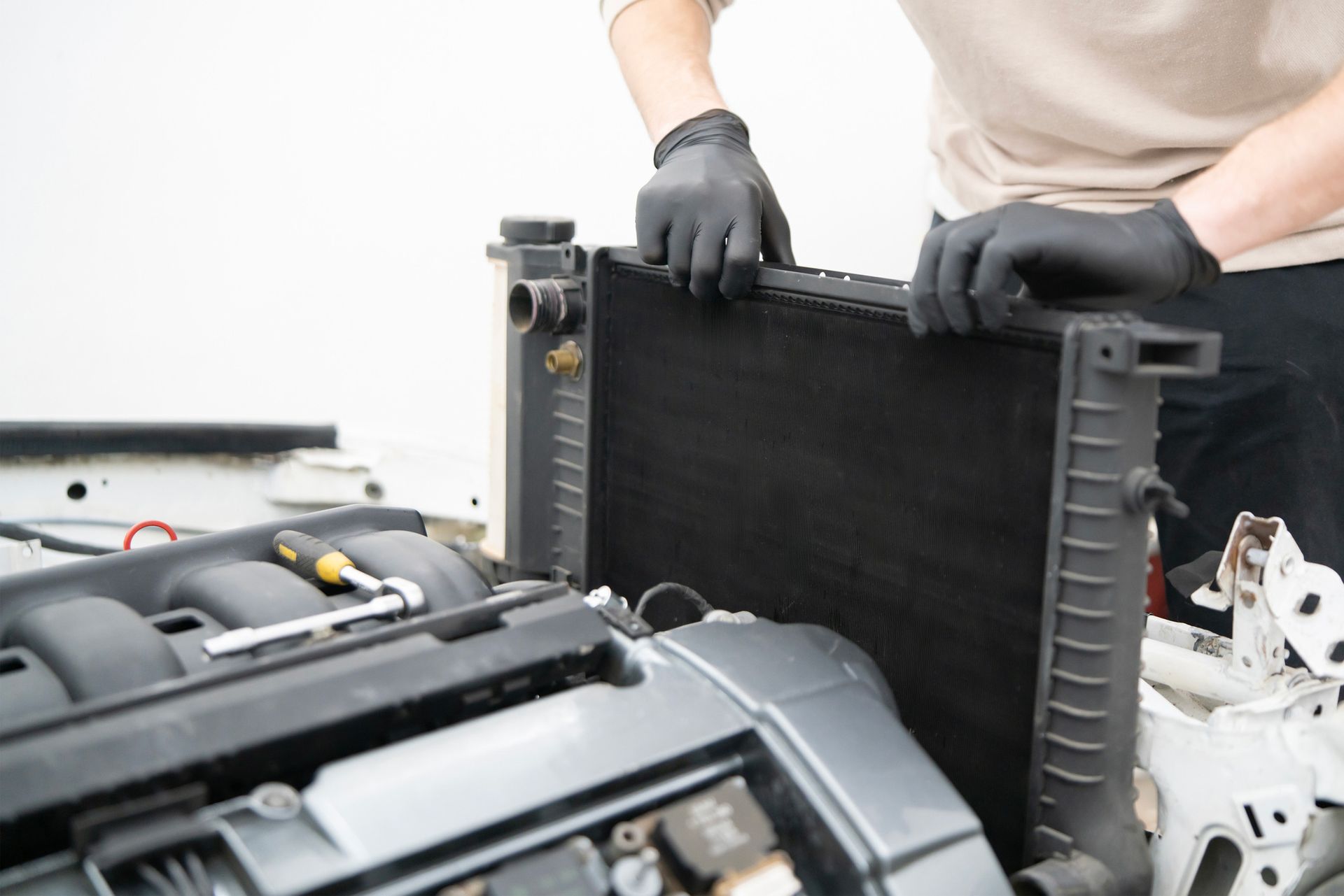 A man is inspecting a car’s radiator. A man is inspecting a car’s radiator.