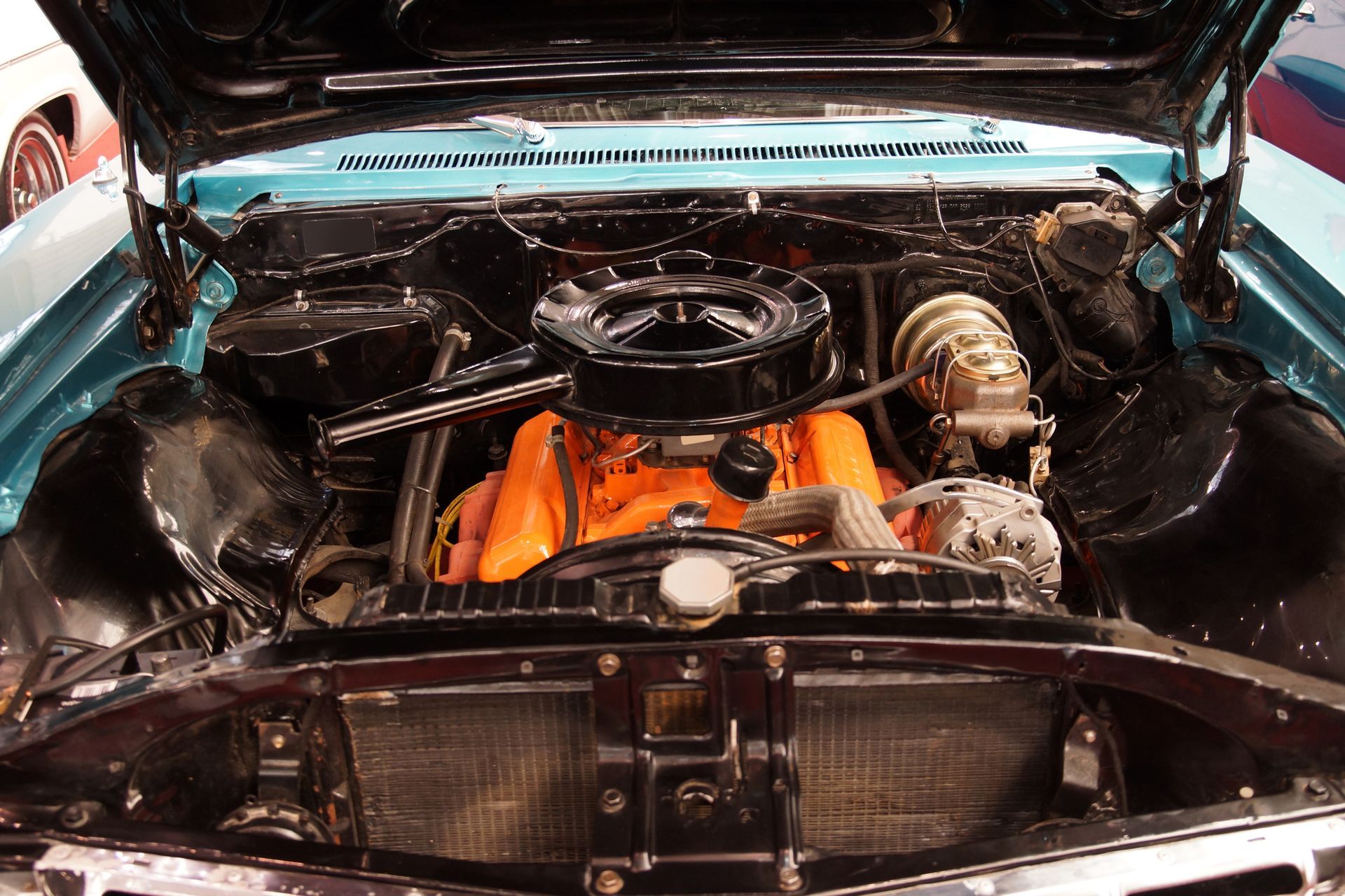 The engine of a blue car is shown with the hood open.