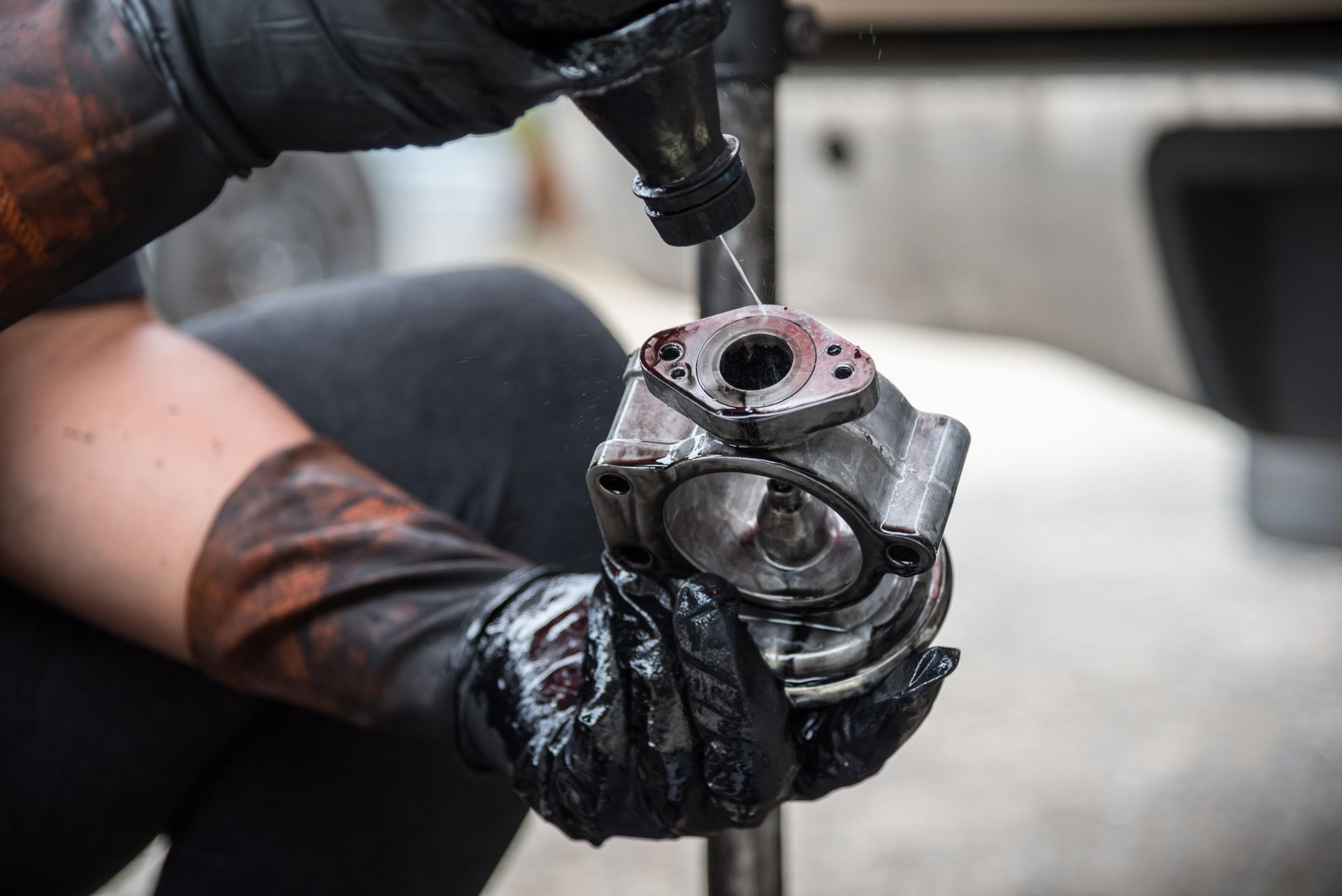 A person wearing black gloves is working on a piece of metal.