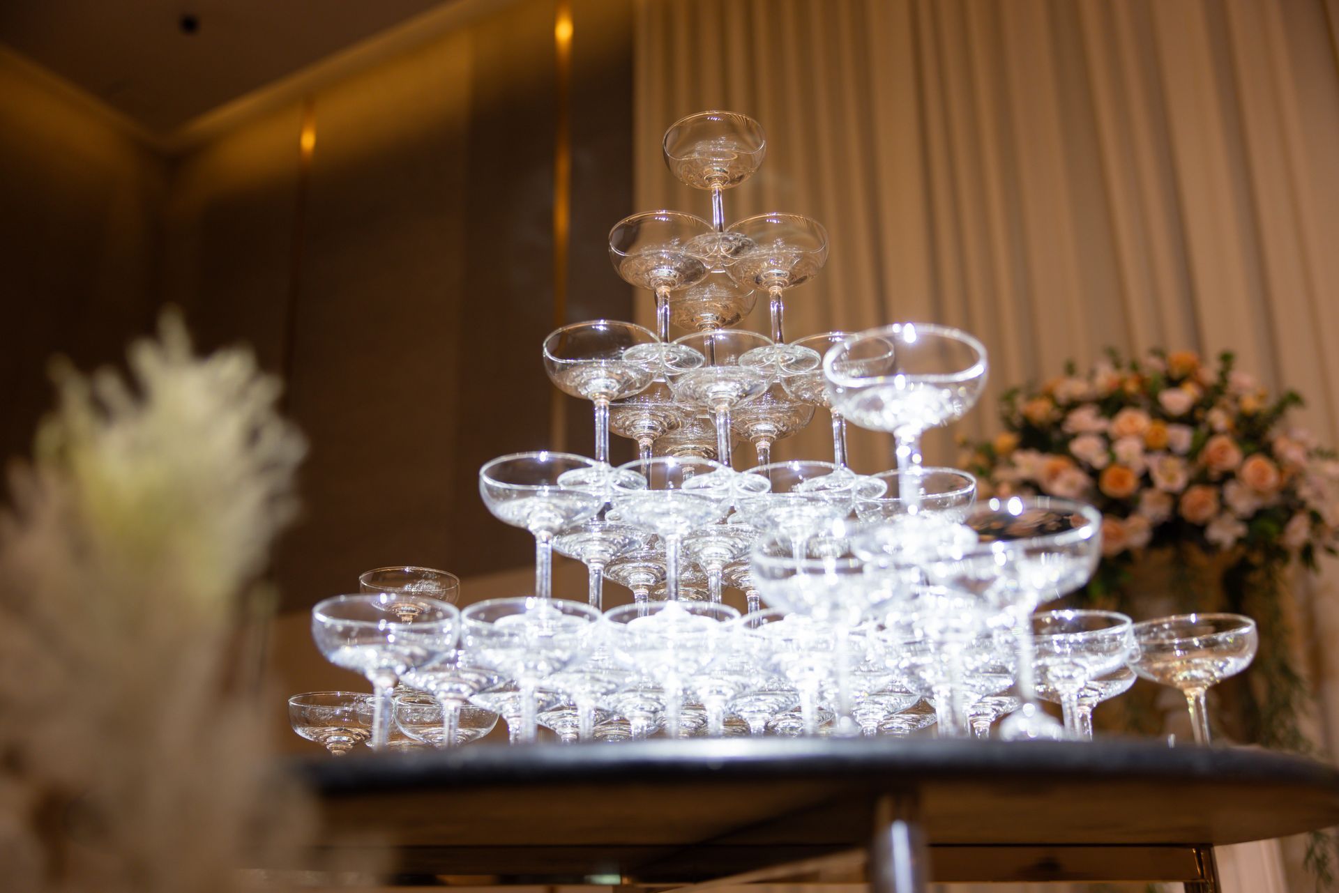 Stacked clear glass dessert dishes glowing on a table in a softly lit banquet hall