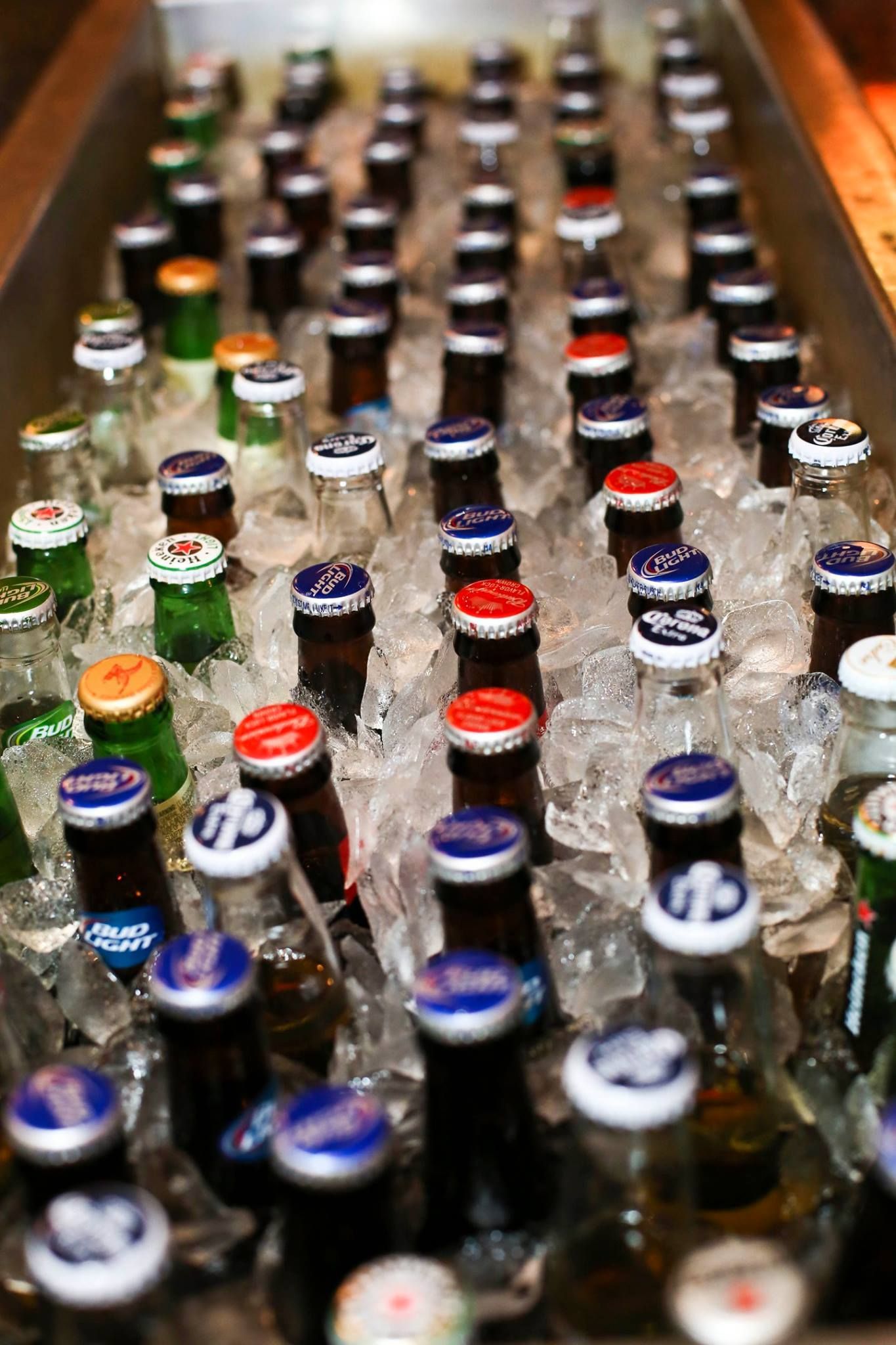 Beer bottles submerged in ice in a cooler; various bottle caps with colors including red, blue, green, and gold.