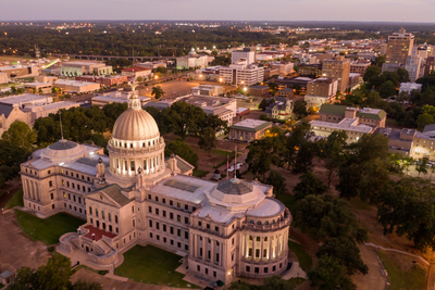 An aerial view of a large building with a dome in the middle of a city.