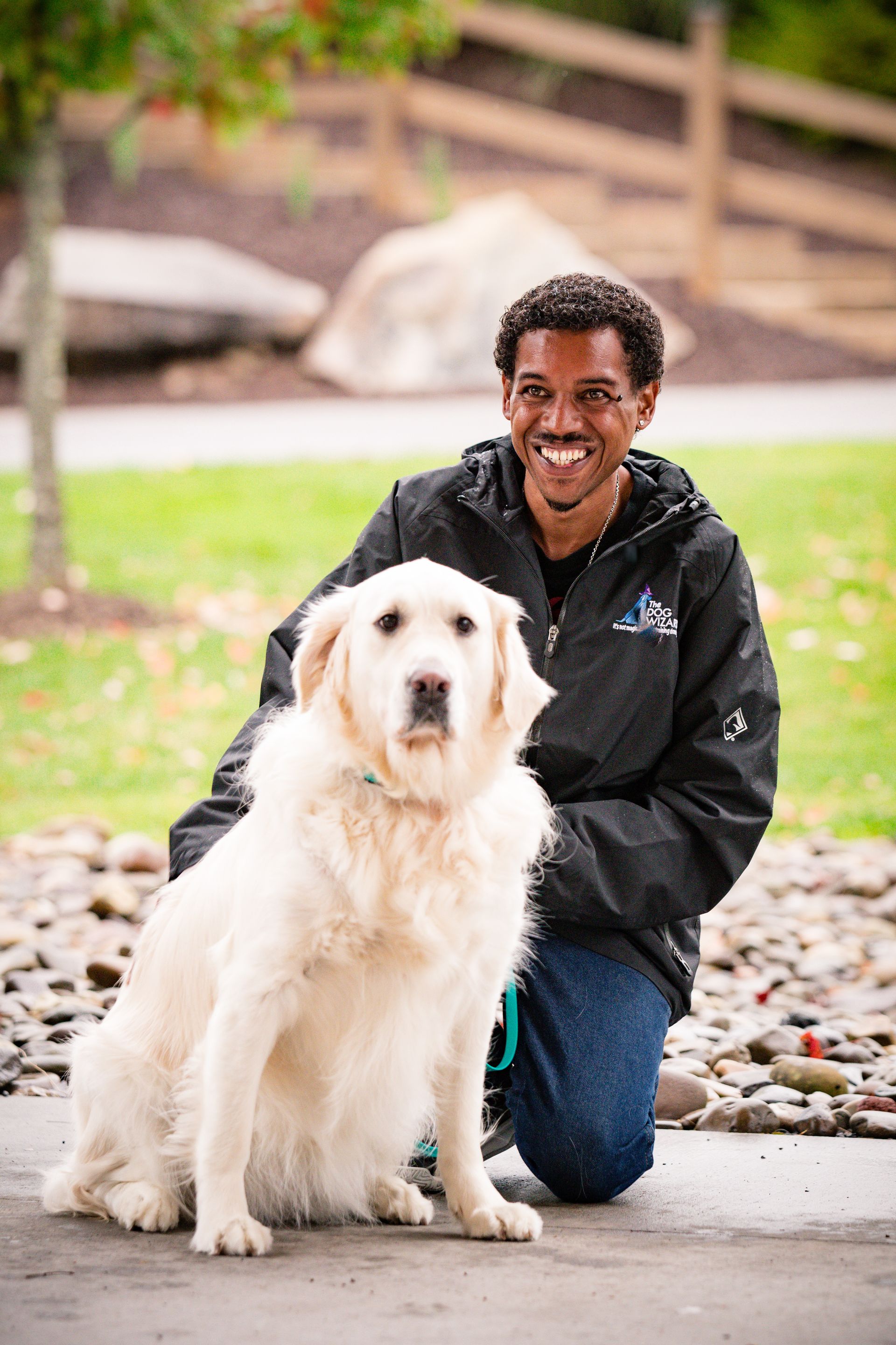 A man is kneeling down next to a white dog.