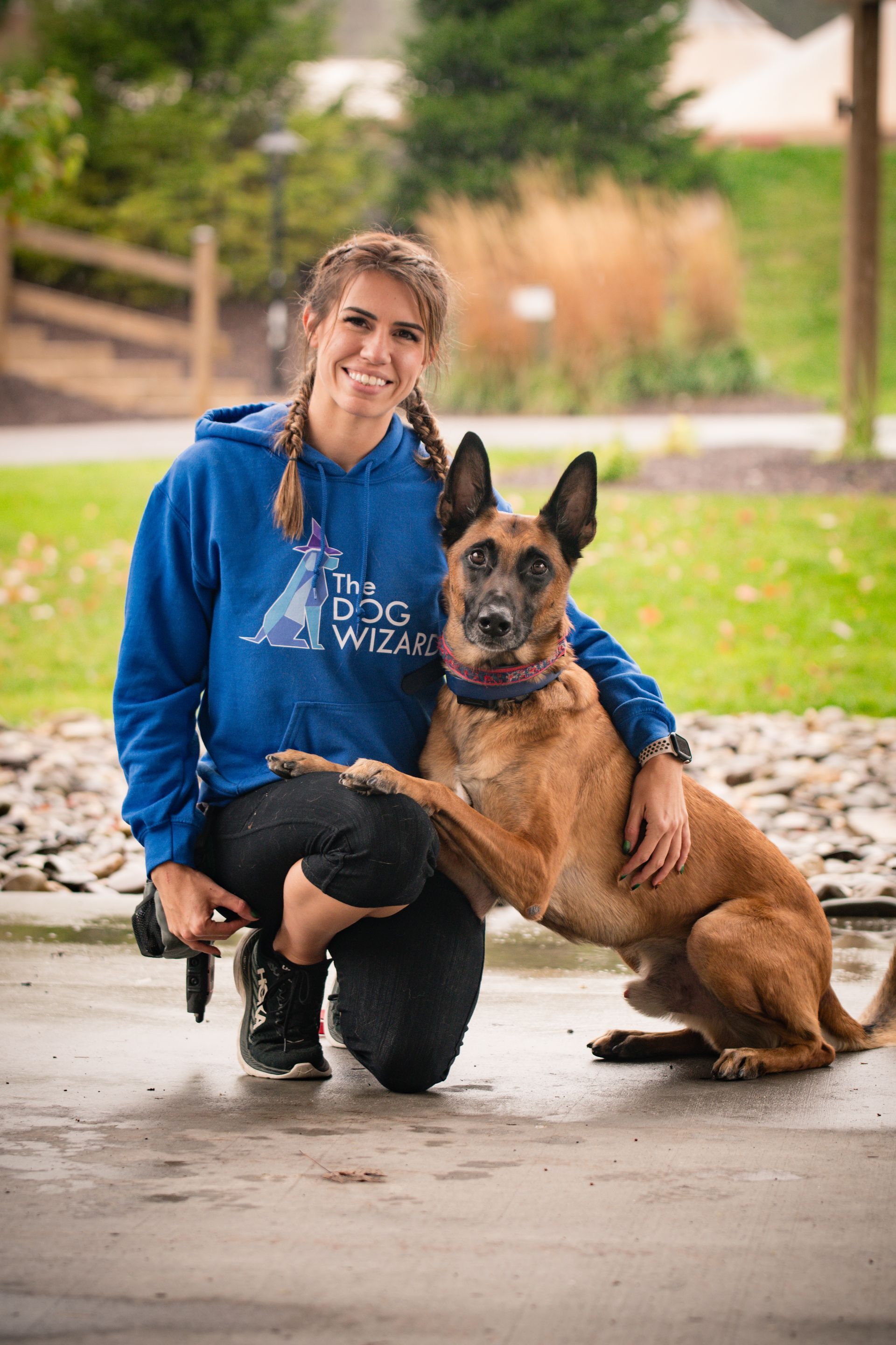A woman is kneeling down next to a brown dog.